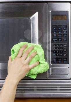 Hand with microfiber rag cleaning outside of microwave oven
