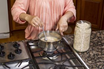 Stirring oatmeal in stainless steel pan on stove top