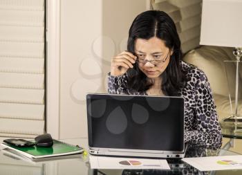 Mature women checking data on her computer while working from home