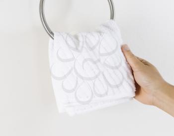Horizontal photo of female hand putting clean white towel on wall hook 