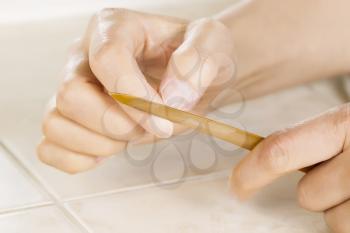 Close up horizontal photo of female hands with golden metal nail file tool in front 