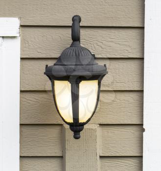 Photo of electric outdoor house lamp on wooden cedar planks attached to house
