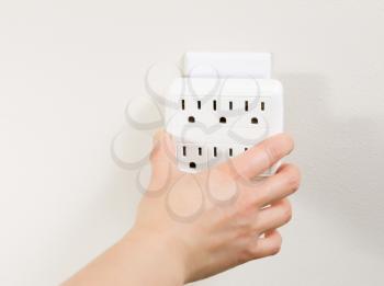 Photo of female plugging in multiple electrical socket units into wall outlet