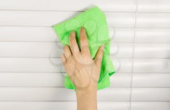 Horizontal photo of female hand cleaning blinds with microfiber cloth
