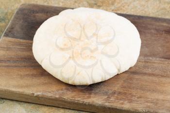 Horizontal photo of fresh pita bread on old wooden cutting board with knife
