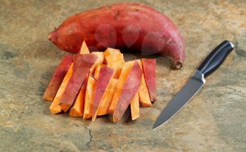 Horizontal photo of freshly cut Yams for cooking with knife and stone board