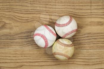 Horizontal top view photo of used baseballs on top of faded wood