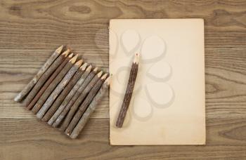 Overhead view of old pencils with tree bark and aged paper on rustic wood