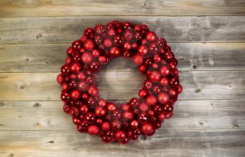 Top view of a large Christmas Wreath made with red ornaments on rustic wood