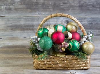 Front view of a basket filled with Christmas ornaments on rustic wood