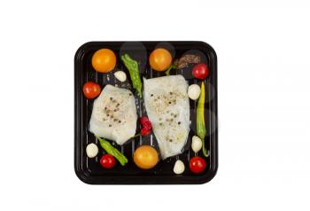 Top view of fresh raw Cod Fish Fillets in cooking pan with tomatoes, garlic, peppers and peppercorn salt isolated on white