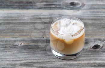 Freshly made Iced Coffee with cream in glass on rustic wood 