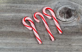 Top view close up of three candy canes placed on rustic wood 