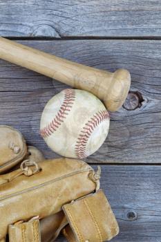 Vertical image of a partial old worn glove, bat and used baseball on rustic wood 