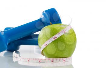 Pristine green apple, two dumbbells, measuring tape isolated on white with reflection. Plenty of copy space.