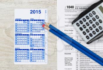 U.S. Tax form 1040 with calculator, calendar and pencils on wooden desktop 