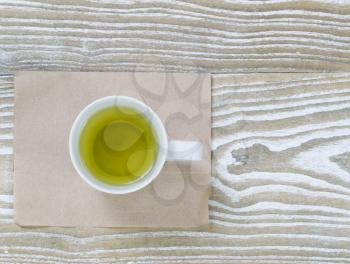 Top view shot of green tea drink with paper napkin on aged white wood surface in horizontal format.