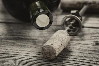 Close up shot of top of wine bottle cork with antique opener in background in vintage style. Layout in horizontal format.   