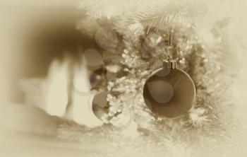 Vintage concept with grain of Christmas ornament hanging on Xmas Tree with raging fireplace in background