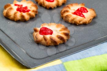 Close up of fruit filled cookies, focus on lead cookie, on baking sheet. 