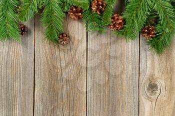 Christmas border with pine tree branches and cones on rustic wooden boards. 