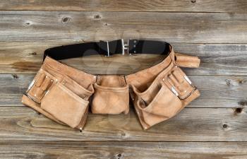 Traditional leather tool belt on rustic wooden floor.