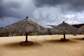Empty beach with straw huts due to incoming storm. 