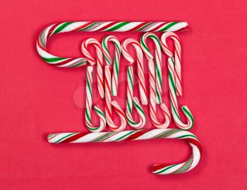 Pattern of peppermint candy canes on red background. 