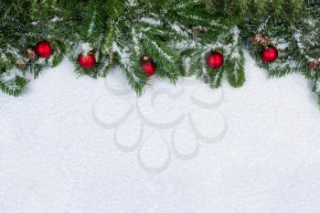 Evergreen branches and red ornaments covered in snow. Christmas concept with plenty of copy space. 
