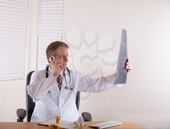 Doctor examining x-ray chart while on the phone