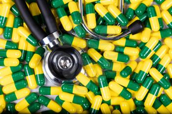 Filled frame of medicine capsules, in green and yellow colors, and stethoscope.