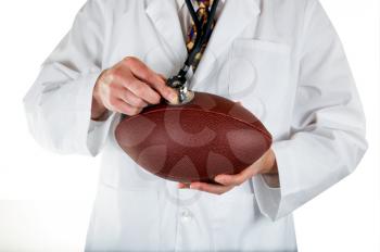 Close up front view of doctor holding football in hands with stethoscope on top