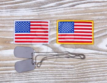 Small USA flag patches and military identification tags on rustic white boards. Fourth of July holiday concept for United States of America.  