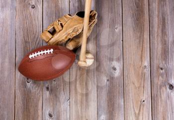 Overhead view of baseball and football equipment on rustic wooden boards. 