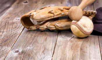 Old baseball equipment on rustic wooden boards. Selective focus on bat handle and ball. 