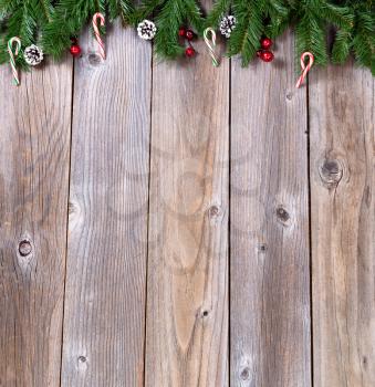 Wooden background for Christmas concept with fir branches, candy canes and red berries. Overhead view with copy space.