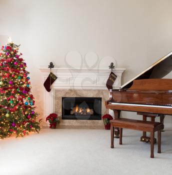 Living room with glowing fireplace, grand piano and decorated Christmas tree for the holidays