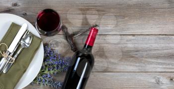 Vintage table setting with fresh flowers and red wine on rustic wood