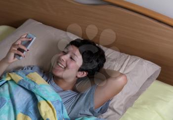Teen girl using wireless mobile technology while in bed