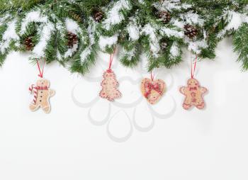Snowy Christmas cookie ornaments hanging in fir tree branches 