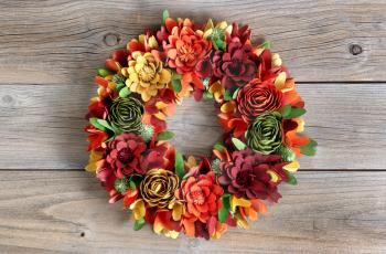 Colorful Wreath made of wooden flowers and leaves on vintage wood background 