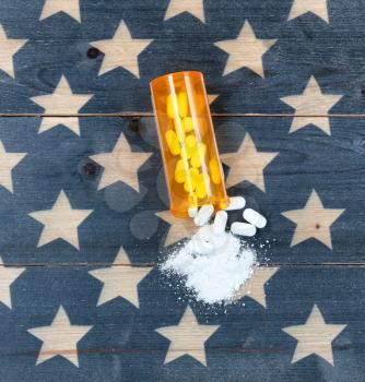 Overhead view of prescription bottle filled with generic opioid pain killer tablets on rustic USA flag in background for drug addiction concept in America  