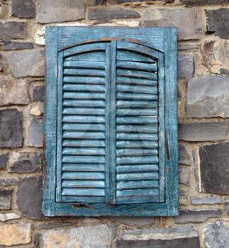 Old wooden window shutters in stone wall 