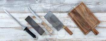 Cooking knives with wet stone and steel for sharpening on white rustic wooden boards 