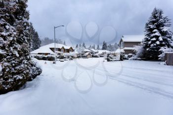 Snow storm in Northwest United States with residential homes and dark skies in background 