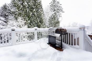 BBQ cooker with bottles of beer during winter time on home outdoor deck 