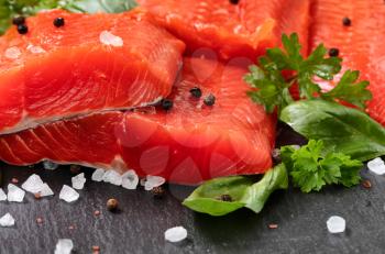 Fresh raw copper river sockeye salmon fillets on natural stone with herbs and seasoning  