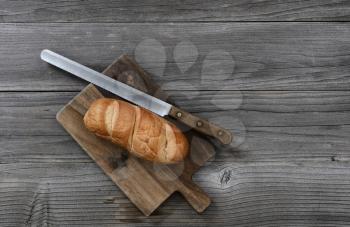 Organic whole wheat loaf with large curated knife on cutting board in top view layout 