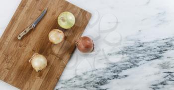 Fresh raw organic onions on marble stone with cutting board