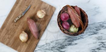 Cutting board with basket of organic raw vegetables to prepare for cooking